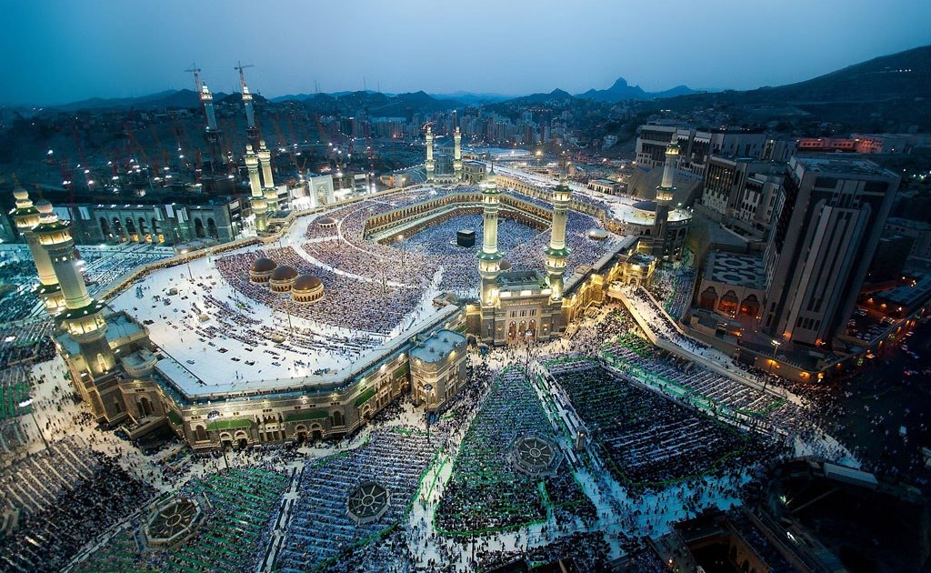 Aerial view of Masjid al-Haram and the Holy Kaaba at night, surrounded by pilgrims